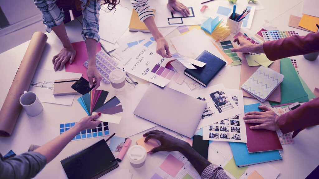 Tisch mit vielen Arbeitsmaterialien und Händen